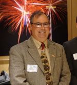 A man in a suit and tie standing next to fireworks.